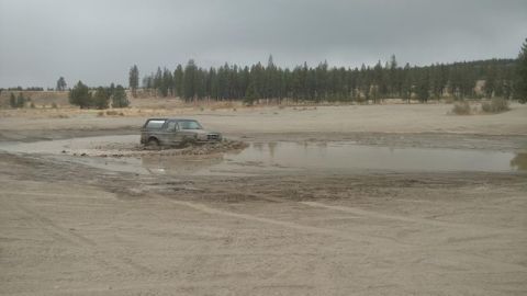1995 Ford Bronco - A Ford Bronco navigates a muddy off-road course under an overcast sky.