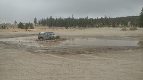 1995 Ford Bronco - A Ford Bronco navigates a muddy obstacle course under an overcast sky.