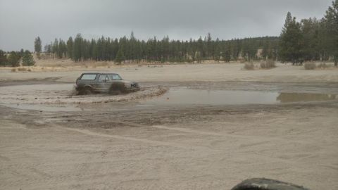 1995 Ford Bronco - A gray 1995 Ford Bronco navigates through a muddy off-road course.
