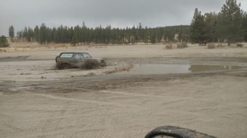 1995 Ford Bronco - Ford Bronco navigating a muddy off-road area on an overcast day.