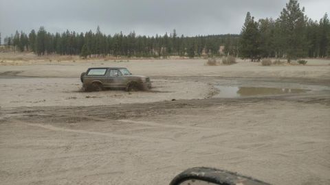 1995 Ford Bronco - A Ford Bronco navigates a muddy off-road course under an overcast sky.