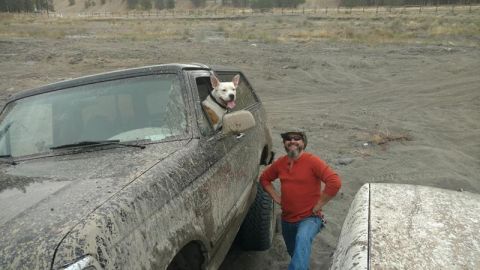 1995 Ford Bronco - A man and his dog pose with a mud-covered SUV in an off-road area.