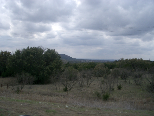 Cloudy sky over a rural landscape with trees and hills in the distance
