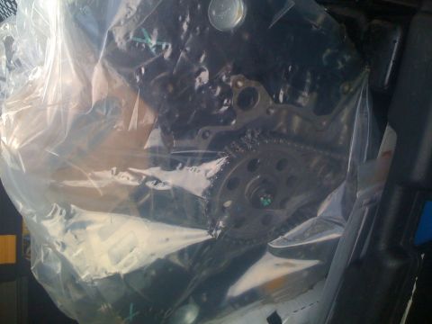 1995 Ford F-150 - Close-up view of engine timing chain and gears, partially obscured by plastic wrapping.