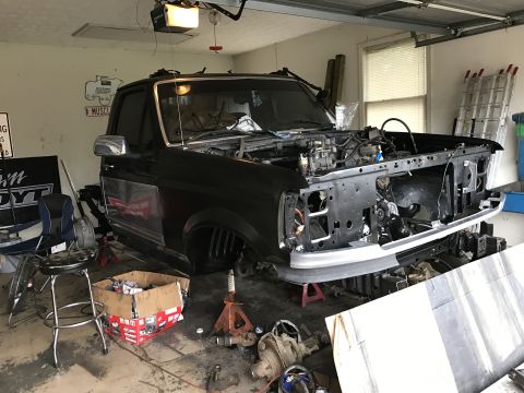 1995 Ford F-150 - A 1995 Ford F-150 is shown in a garage with its front end disassembled for repairs or modifications.