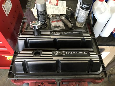 1995 Ford F-150 - Two Ford Racing valve covers are displayed on a workbench alongside automotive supplies and tools.
