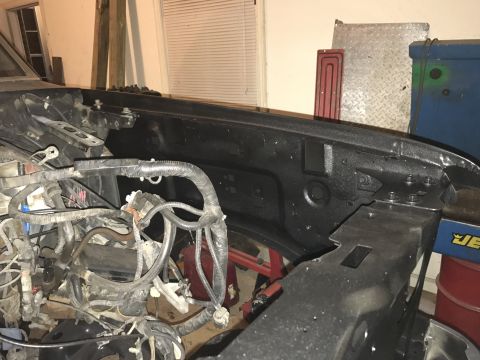 1995 Ford F-150 - The engine bay of a vehicle is shown, a complex wiring harness and a black fender liner.