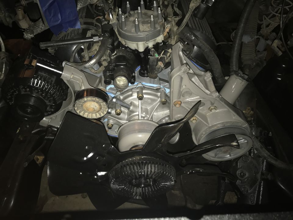Close-up of a vehicle engine bay showing the alternator, water pump, and fan shroud