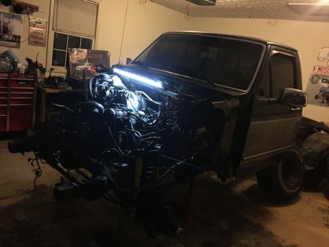 1995 Ford F-150 - A Ford truck is shown in a garage with its engine compartment exposed and engine removed.
