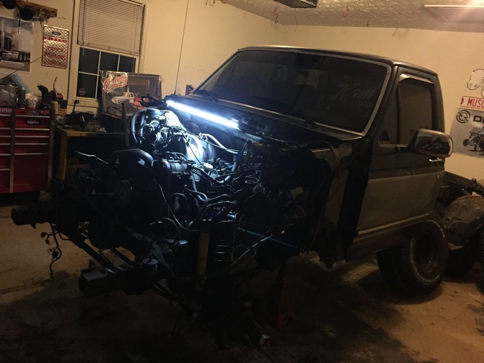Ford truck with engine removed, viewed from the front in a garage