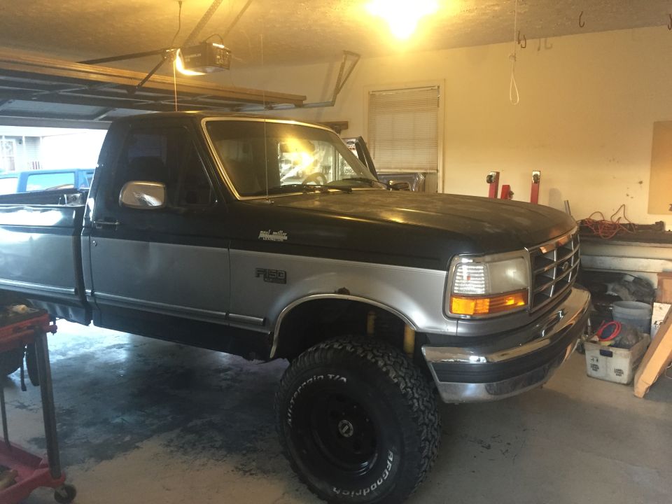 1995 Ford F-150 pickup truck, black and silver, parked in a garage, side view.