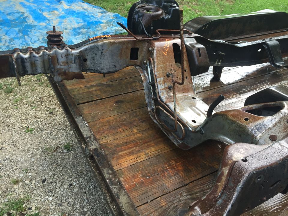 Rusty vehicle frame on a wooden trailer.