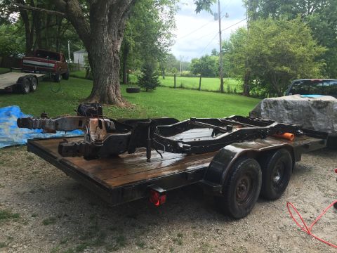 1995 Ford F-150 - A disassembled vehicle frame, likely from a pickup truck, sits on a flatbed trailer outdoors. The frame appears to be painted black and is…