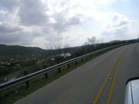 1994 Ford Bronco - A scenic view of a lake and rolling hills from a car driving along a highway.