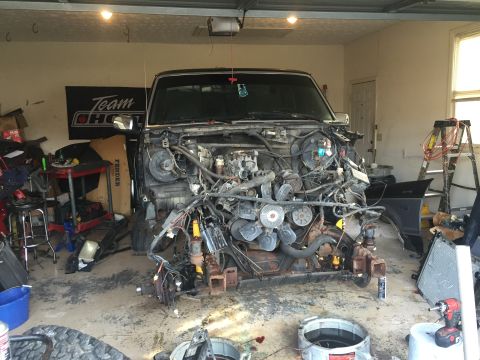 1995 Ford F-150 - A disassembled vehicle, likely a pickup truck, is parked in a garage with its engine and front end removed. Various tools and parts are sca…