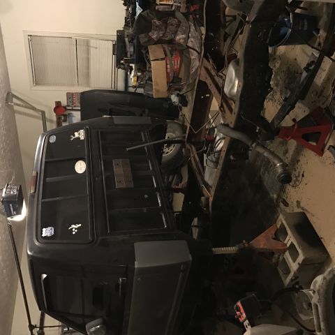 1995 Ford F-150 - A black pickup truck bed and cab are shown in a garage setting, partially disassembled. The truck is supported by jack stands and surrounde…