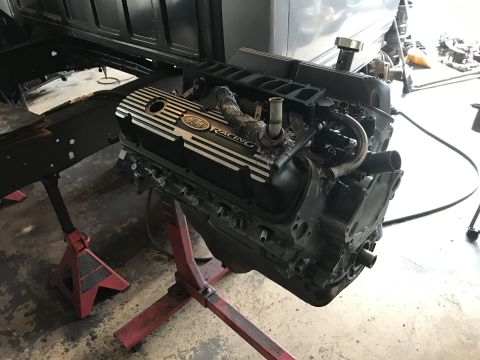 1995 Ford F-150 - A Ford V8 engine with Ford Racing valve covers is supported by red jack stands in a garage setting.