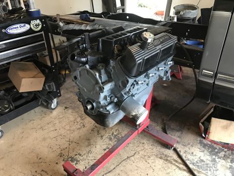 1995 Ford F-150 - A gray Ford V8 engine is mounted on a red engine stand in a garage. The engine has black Ford Racing valve covers and is connected to a bla…