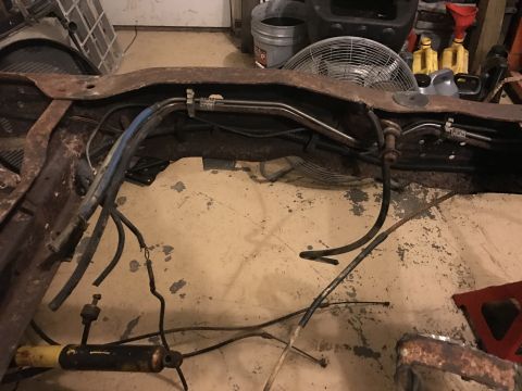 1995 Ford F-150 - A rusty vehicle frame is shown with various hoses and wires attached. A large industrial fan is visible behind the frame.