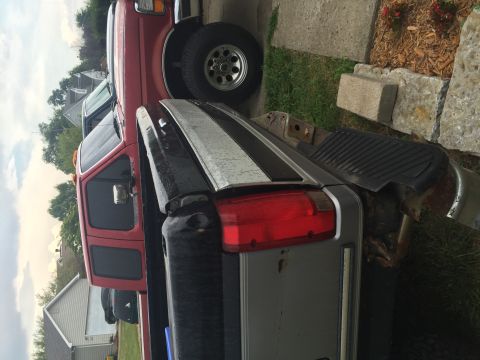 1995 Ford F-150 - A close-up, side view of the rear of a silver pickup truck with a red cab. The truck is parked next to a red pickup truck.