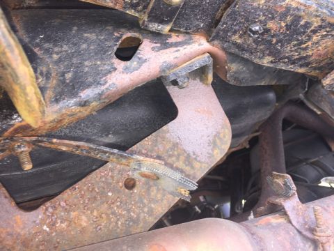 1995 Ford F-150 - This is a close-up, low-angle shot of the heavily rusted undercarriage of a vehicle, likely a truck, showing various metal components and e…