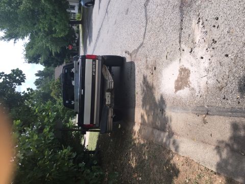 1995 Ford F-150 - The rear driver's side of a black and silver Ford pickup truck is shown parked on a residential street. The truck has a chrome bumper and a…