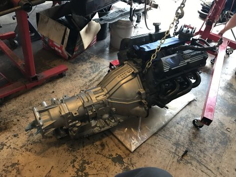 1995 Ford F-150 - A Ford V8 engine and transmission assembly is suspended by a chain hoist over a concrete floor in a garage. The engine has black valve cove…