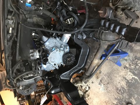 1995 Ford F-150 - A partially assembled engine and drivetrain components are laid out on a concrete floor, likely in a garage or workshop setting. The engine…