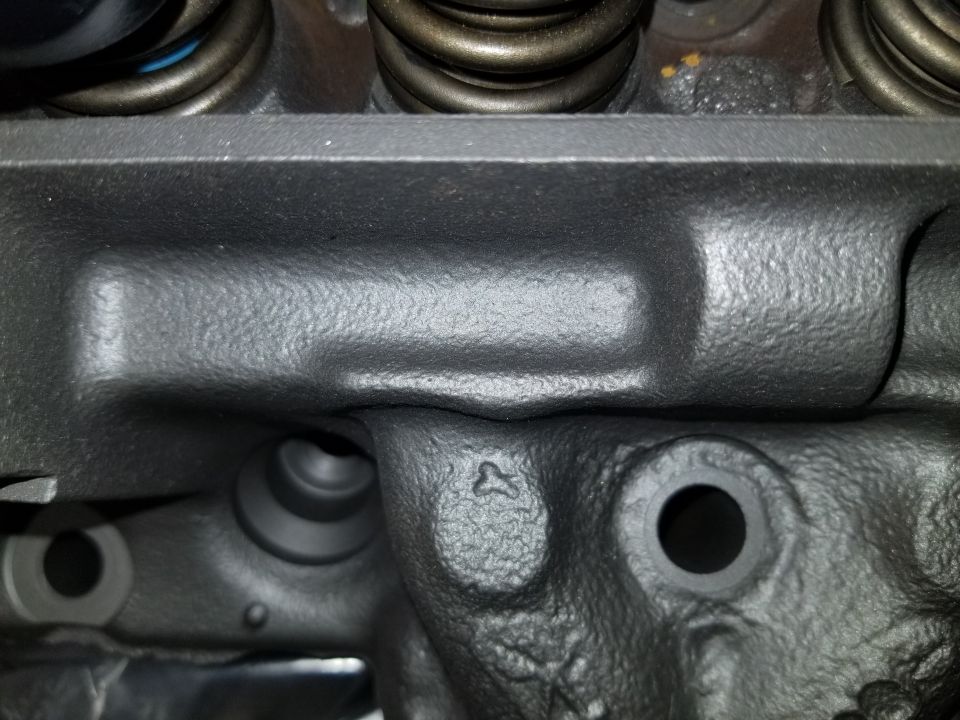 Close-up of a dark gray V8 engine cylinder head with valve springs and ports.