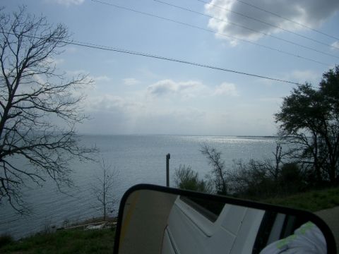 1994 Ford Bronco - A reflection in a side mirror shows a portion of a white vehicle against a backdrop of a lake and sky.