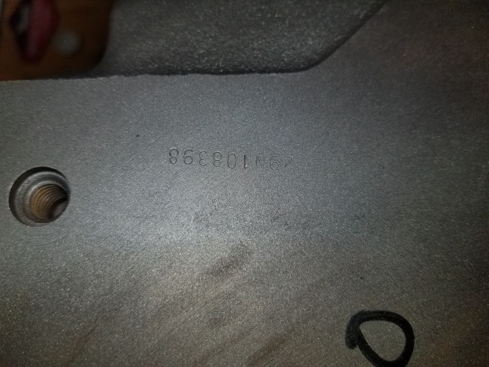 Cast metal part stamped with part number F2VE-10E398 and a threaded boss