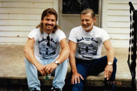 1989 Ford Bronco - Two men are sitting on a porch. The man on the left has a mullet and is wearing a white t-shirt and light blue jeans. The man on the right…