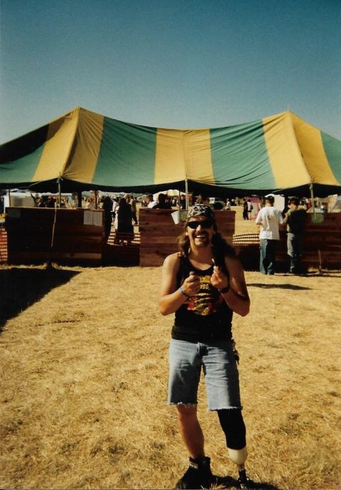 1989 Ford Bronco - A man with a prosthetic leg smiles at the camera while holding two cigarettes. He is standing in front of a large yellow and green striped…