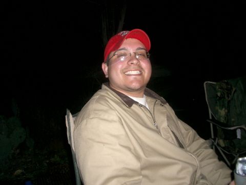 1994 Ford Bronco - A man in casual outdoor attire is captured smiling while seated in a camping chair at night.