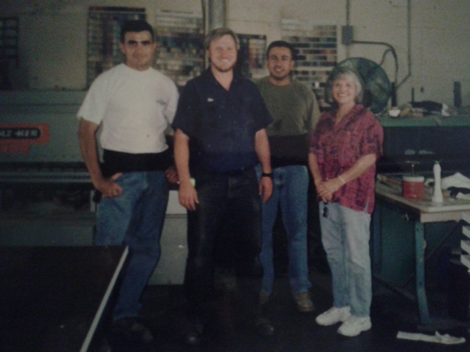 Four people posing for a photo in a workshop.