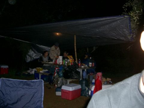 1994 Ford Bronco - Camp scene at night with people gathered under a tarp for shelter.