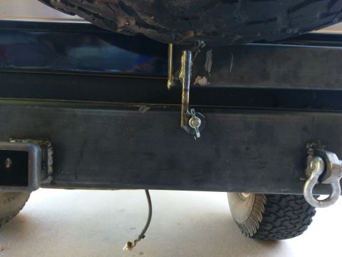 1988 Ford Bronco - A close-up view of a custom rear bumper on a vehicle, showing a tire mounted above it, a hitch receiver on the left, and a tow shackle on t…