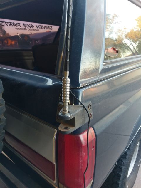 1988 Ford Bronco - A close-up view of the rear passenger side corner of a dark blue SUV, showing a custom-mounted antenna and part of the taillight assembly.…