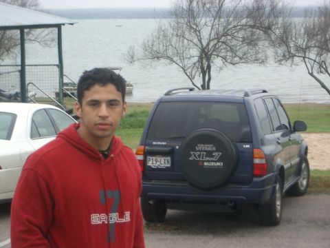 1994 Ford Bronco - A blue Suzuki Grand Vitara XL-7 is parked by a lake, with a person standing in front of it.