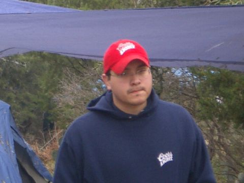 1994 Ford Bronco - A man in a red cap and blue hoodie stands outdoors near a tent.