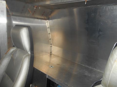 1992 Ford Bronco - Interior view of a vehicle, showing a worn leather seat on the left and a metallic dashboard and wall paneling on the right. The interior a…