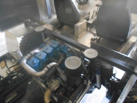 1992 Ford Bronco - The engine bay of a vehicle is shown, featuring a blue engine with twin turbochargers and silver exhaust piping. Two black seats are visibl…