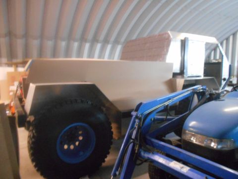 1992 Ford Bronco - A custom-built vehicle, possibly a trailer or a truck bed, is under construction inside a Quonset hut. A blue tractor with a front loader i…