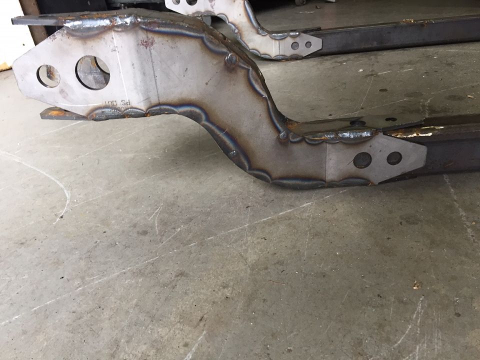 Welded metal frame parts with visible weld beads and bolt holes