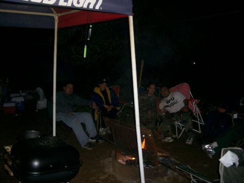 1994 Ford Bronco - A group of friends enjoy a night out camping by a fire, with a cooler and grill nearby.