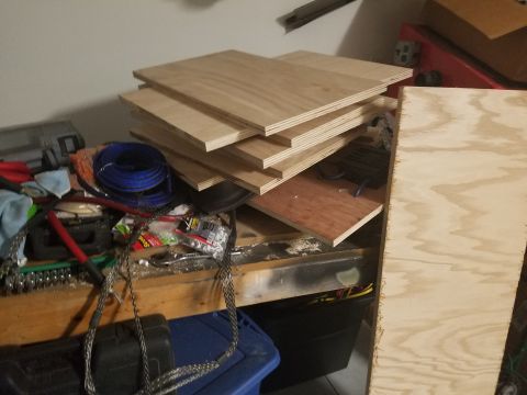 1994 Ford Bronco - A cluttered workbench displays stacks of plywood alongside various tools and electrical wiring.