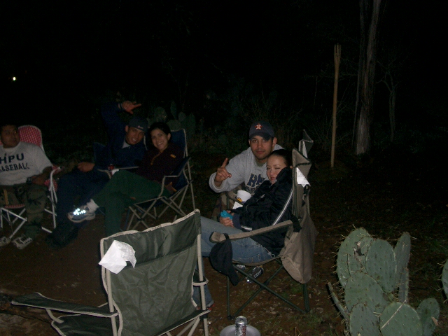 Group of people sitting in camping chairs at night with cacti in the foreground