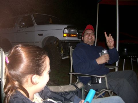 1994 Ford Bronco - A white 1994 Ford Bronco with a lifted suspension is visible in the background of a nighttime outdoor gathering.