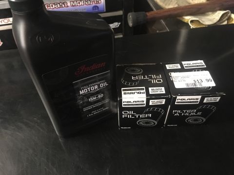 2010 Dodge Challenger - Motor oil and oil filters are laid out on a dark surface, with visible branding for Indian Motorcycle and Polaris.