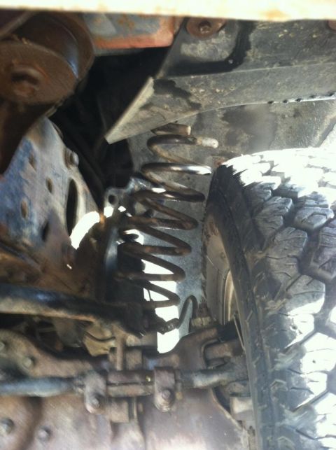 1987 Ford Bronco II - Close-up view of the undercarriage, focusing on the suspension spring and tire of an unidentified vehicle.